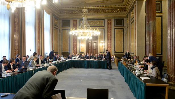 Ein großer Konferenzraum mit Personen an Tischen unter einem Kronleuchter.