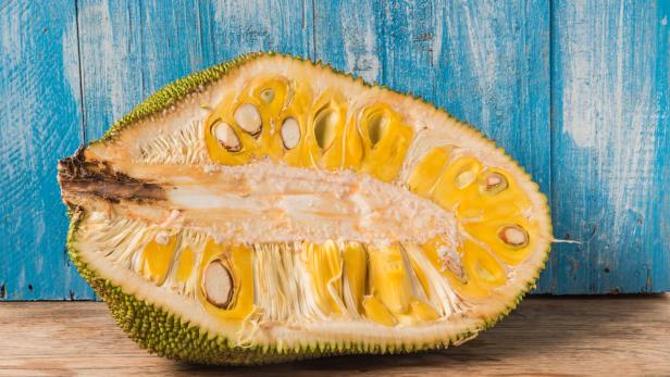 Eine aufgeschnittene Jackfrucht liegt auf einem Holztisch.