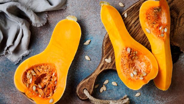 Halbierte Butternusskürbisse liegen auf einem Schneidebrett.