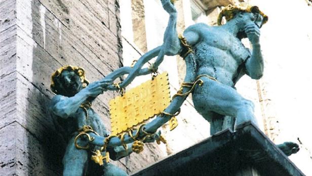 Zwei bronzene Figuren halten ein goldenes Schild mit der Aufschrift „LEIBNIZ KEKS“.