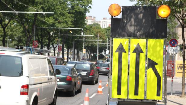 Gelbe Verkehrsschilder mit Pfeilen weisen auf eine Baustelle in der Stadt hin.