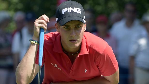 Ein Golfer mit rotem Hemd und schwarzer Kappe konzentriert sich auf seinen Putt.