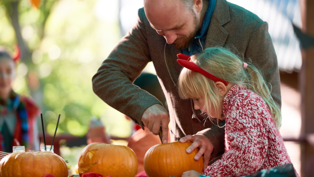 Vater und Tochter schnitzen gemeinsam einen Kürbis für Halloween.