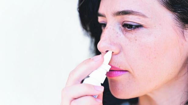 Relaxed young woman using nasal spray