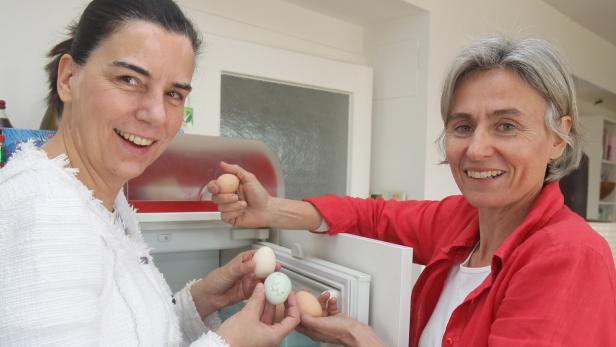 Zwei Frauen stehen vor einem Kühlschrank und halten Eier in den Händen.