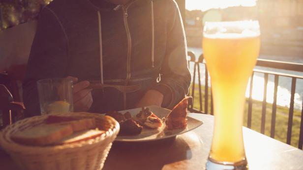 Eine Person isst im Biergarten bei Sonnenuntergang.