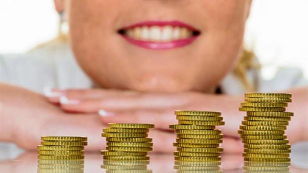 Eine Frau betrachtet aufsteigende Euromünzen-Stapel.