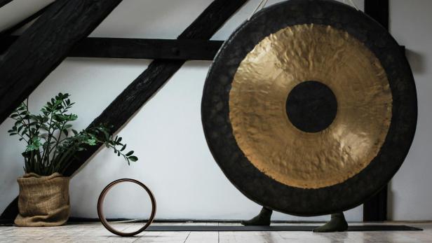 Ein Gong steht in einem Raum mit Holzbalken und einer Zimmerpflanze.