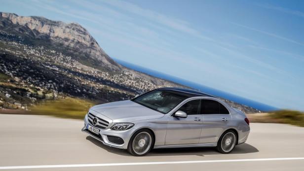 Eine silberne Mercedes-Benz C-Klasse fährt auf einer Küstenstraße.