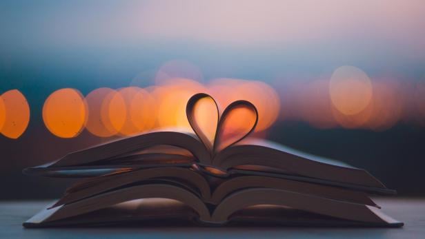 Ein Buch liegt aufgeschlagen da, die Seiten formen ein Herz.