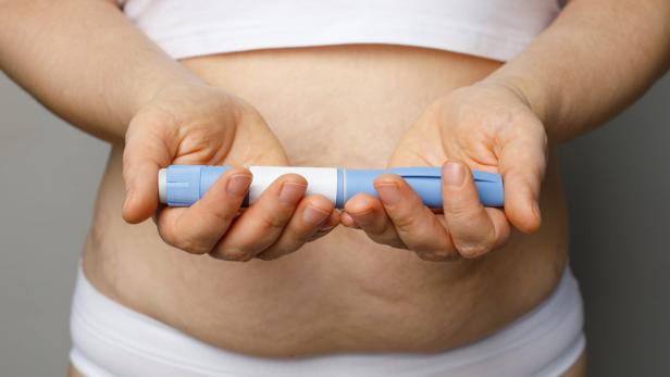 Eine Frau hält eine Abnehmspritze in der Hand.