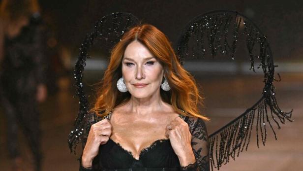 Carla Bruni läuft in schwarzer Spitze und herzförmigen Flügeln über einen Laufsteg.