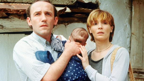 Ein Mann und eine Frau halten ein Baby im Arm.