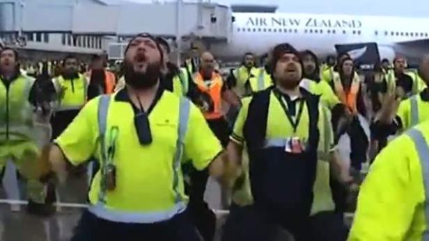 Flughafenmitarbeiter von Air New Zealand führen einen Haka vor einem Flugzeug auf.