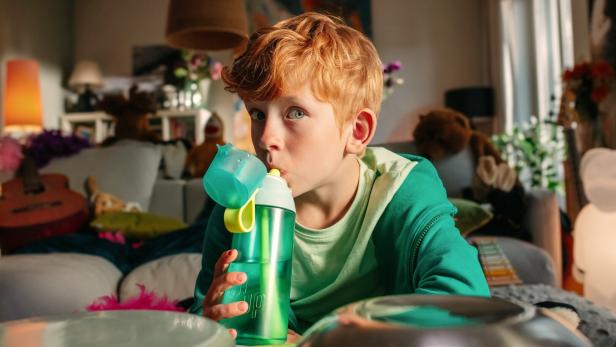 Ein Bub trinkt aus einer Air up Flasche.