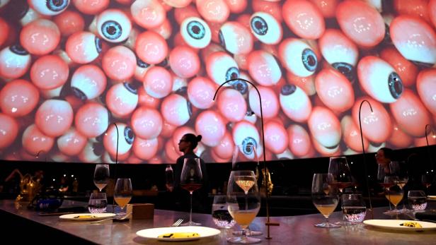 Ein gedeckter Tisch, darüber eine Kuppel auf der Augäpfel projeziert werden.