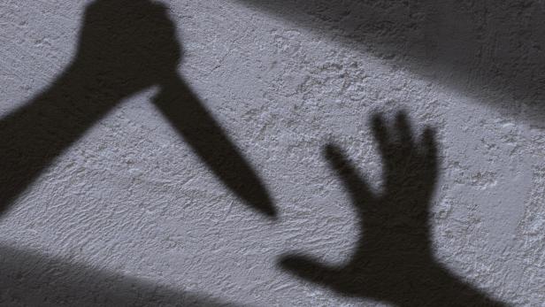 Der Schatten einer Hand mit einem Messer bedroht eine andere Hand.