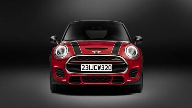Ein roter Mini Cooper John Cooper Works vor einem dunklen Hintergrund.