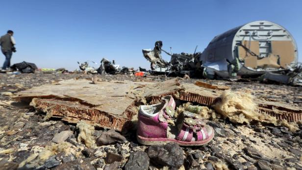 Am Boden liegen Trümmer eines Flugzeugs und ein einzelner Kinderschuh.
