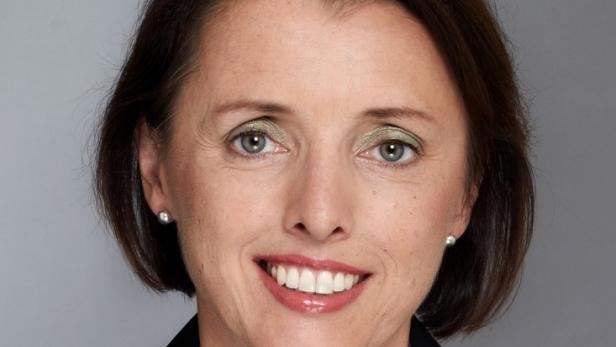 Porträt einer lächelnden Frau mit kurzem braunem Haar und Ohrringen.