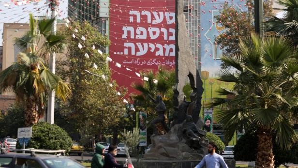 Menschen gehen am 27. Oktober 2024 an einem Plakat in Teheran vorbei, auf dem in Farsi und Hebräisch steht: "Ein weiterer Sturm wird kommen". Am 26. Oktober führte Israel Luftangriffe auf Militärstandorte im Iran durch.