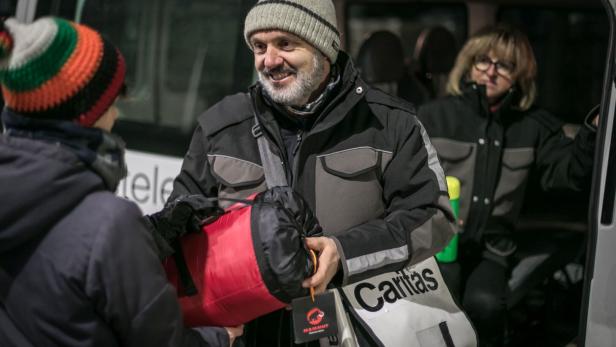 Mann überreicht Schlafsack bei Kältebus