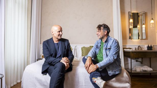 Bernd Schlacher und Axel Halbhuber sitzen zum Interview auf einem Hotelbett