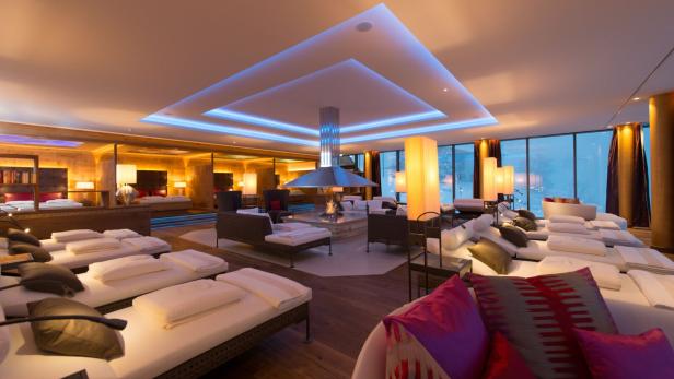 Ein luxuriöser Entspannungsraum mit Liegen, Kamin und gedämpfter Beleuchtung.