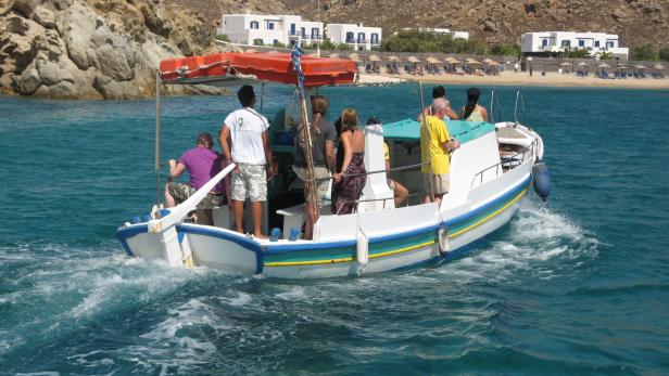 Kleines Taxiboot im Meer vor Mykonos mit wenigen Passagieren