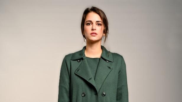 Model mit grüner Hose, grünem Oberteil und grünem Mantel.