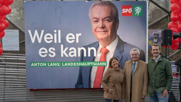 Drei Personen vor Plakat