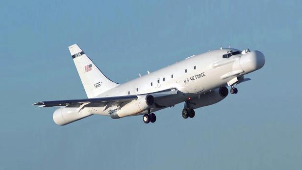 Ein weißes Flugzeug fliegt vor blauem Himmel
