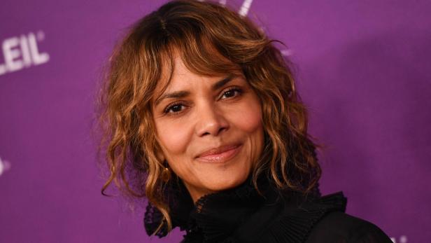 Ein Porträt von Halle Berry vor einem violetten Hintergrund.