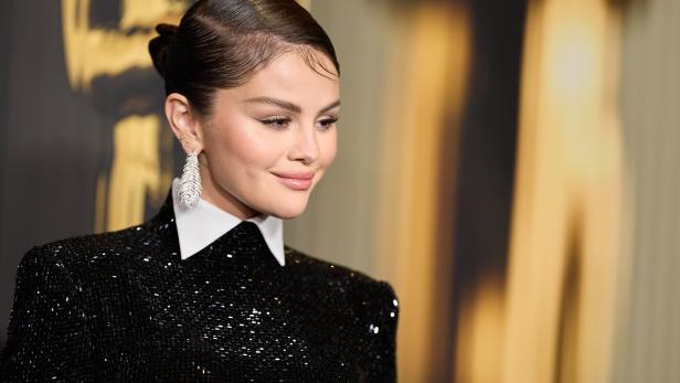 Selena Gomez trägt ein glitzerndes schwarzes Kleid und auffällige Ohrringe.