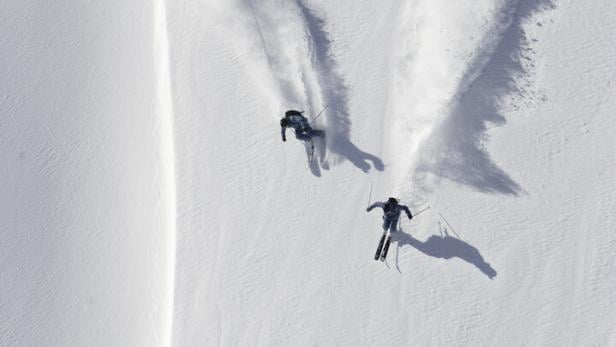 Zwei Skifahrer im Pulverschnee bei einer Abfahrt