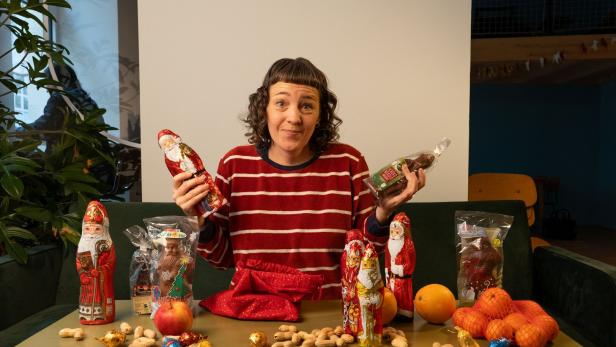 Eine Frau präsentiert Schoko-Nikoläuse und andere Süßigkeiten auf einem Tisch.