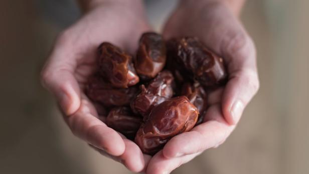 Eine Person hält Datteln in den Händen.
