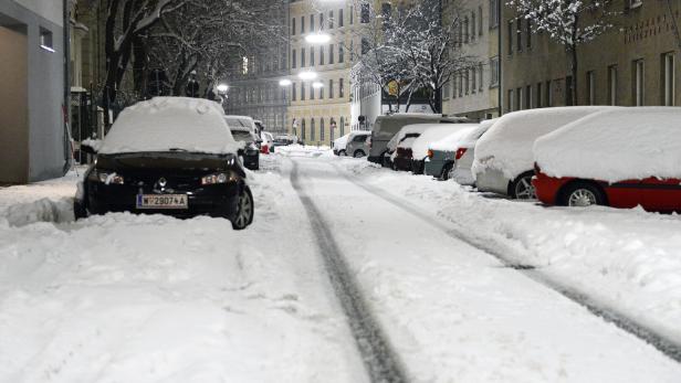 Eine Straße mit parkenden Autos, die mit Schnee bedeckt sind.