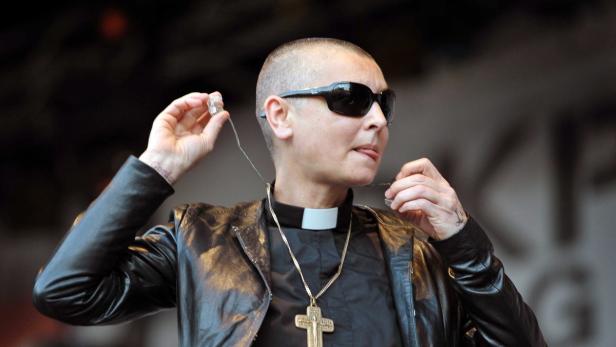 Sinéad O'Connor mit Sonnenbrille, Priesterkragen und großem Kreuz-Anhänger.