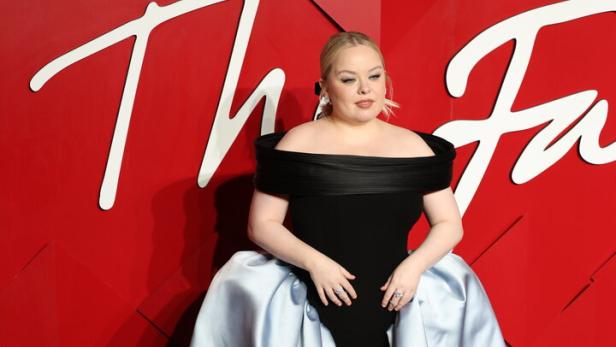 Nicola Coughlan in einem schwarzen Kleid mit hellblauer Schleppe auf dem roten Teppich.