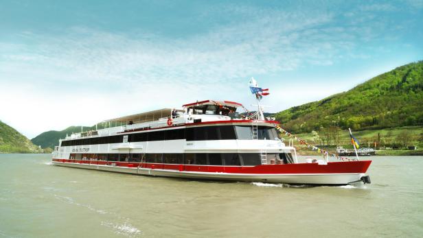 Die MS Admiral Tegelthoff auf der Donau. Im hintergrund sind Weinberge zu sehen. Der Himmel ist blau.