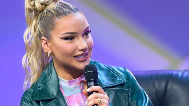 Seit ihrem Hit "Bauch Beine Po" ist Shirin David nicht mehr in der Lage, in eine Pilatesstudio zu gehen. Das hat einen traurigen Grund. Shirin David mit einem Mikrofon in der Hand