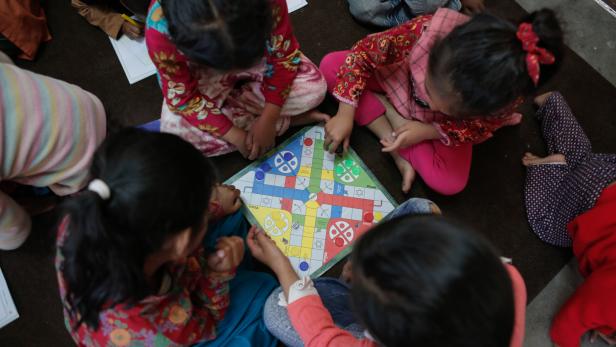 Vier Mädchen spielen in einem Kinderheim in Nepal ein Brettspiel.