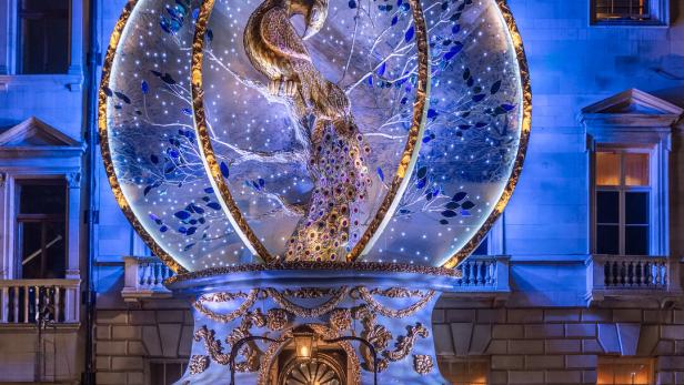 Ein großer Pfau steht in einer Glaskugel: Die Dekoration füllt eine ganze Fassade aus.