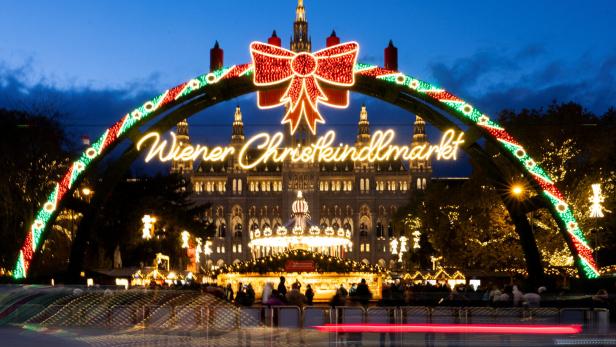Adventmarkt am Rathausplatz beleuchtet mit Bogen, Aufschrift und Masche