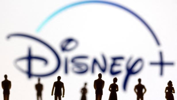 FILE PHOTO: Toy figures of people are seen in front of the displayed Disney + logo, in this illustration