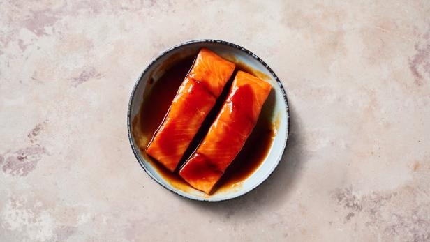 Zwei Lachsfilets in Teriyaki-Marinade in einer Schüssel.