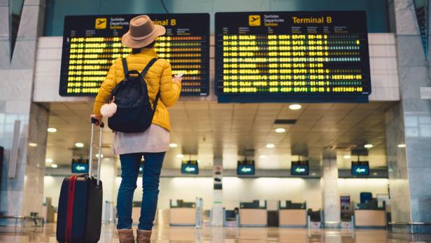 Frau schaut am Flughafen auf Anzeigentafel 