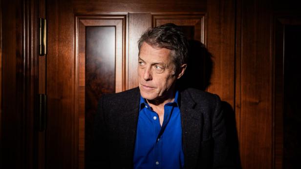Schauspieler Hugh Grant Porträt von Hugh Grant vor einer Holztür.