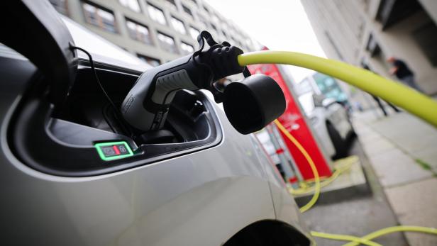 Ein Elektroauto wird an einer Ladestation mit einem gelben Kabel aufgeladen.